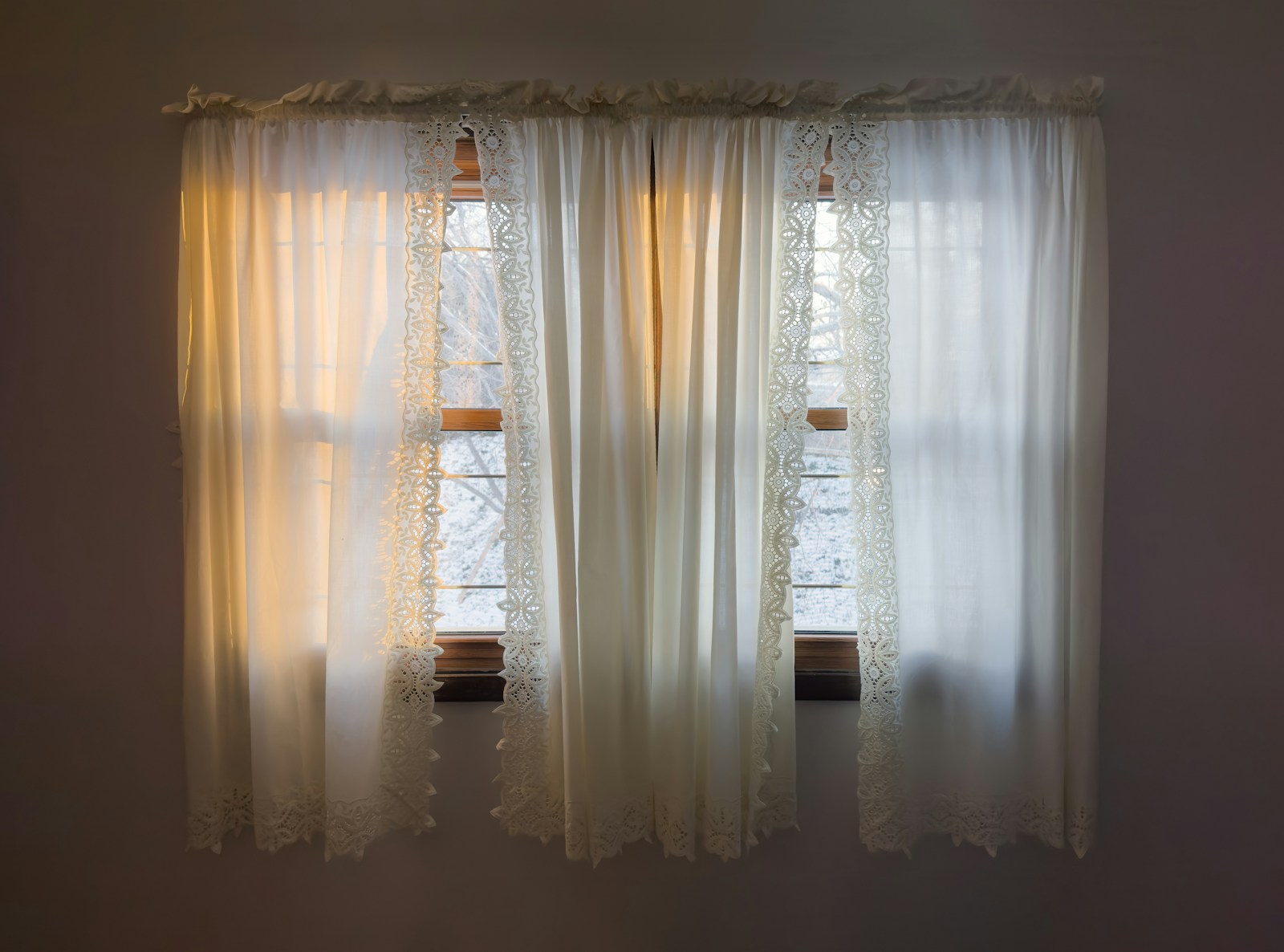 Morgenlicht durch Spitzengardinen in einem ruhigen Zimmer
